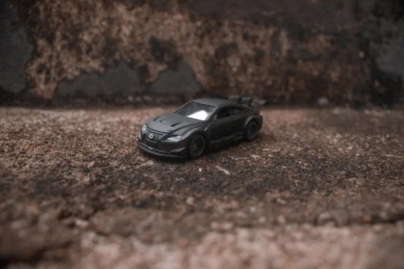 A dark grey sports car on a textured surface